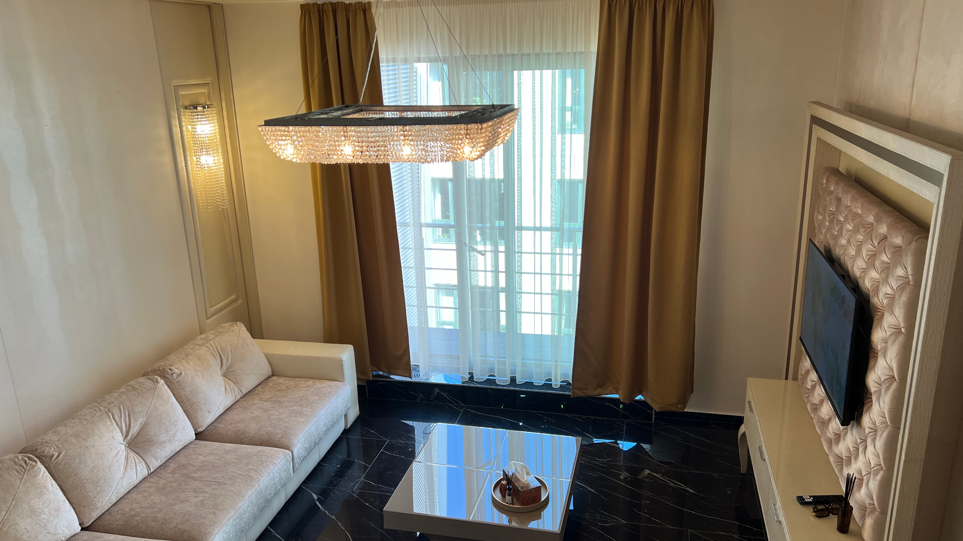 Living room with crystal chandelier, velvet sofa and black marble floors